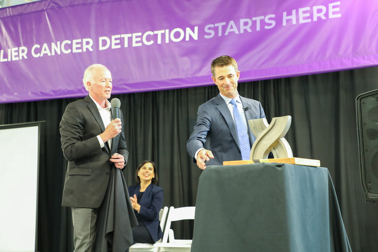 Rich Lynch, chairman of J.H. Findorff & Son Inc., presents a gift to Kevin Conroy from the construction crews -- a metal helix in the shape of the X in Exact Sciences' logo.
